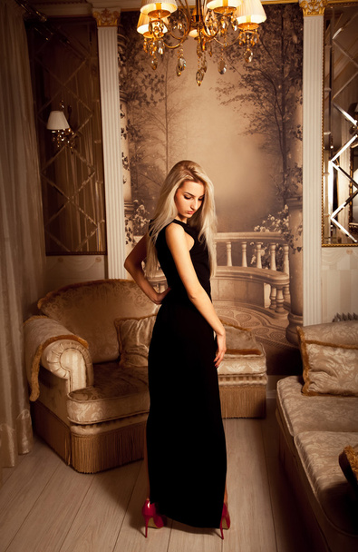 Slim sexual blonde woman in long black dress and red high heels - Fotó, kép