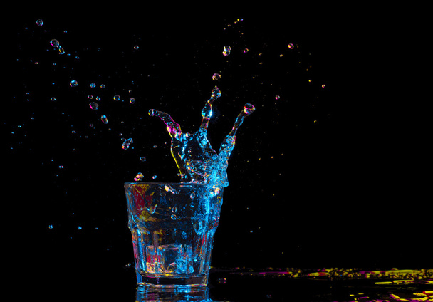 cocktail in glass with splashes on dark background. Party club entertainment. Mixed light. - Foto, Imagen