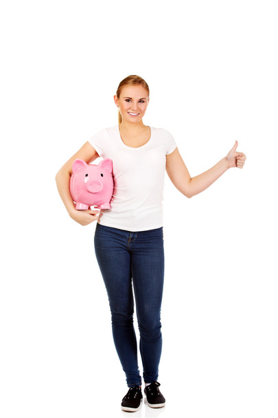 Happy young woman holding piggybank - Valokuva, kuva