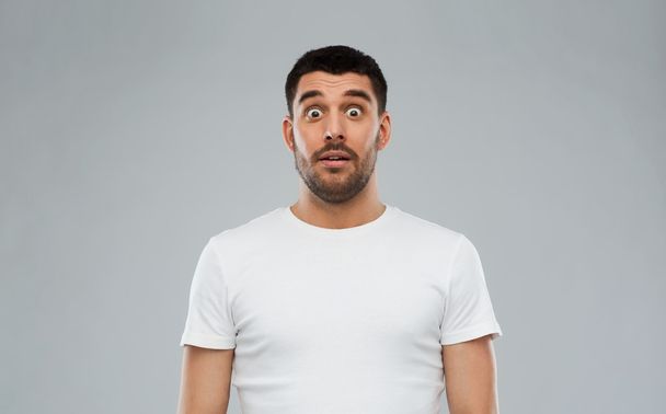 scared man in white t-shirt over gray background - Фото, зображення