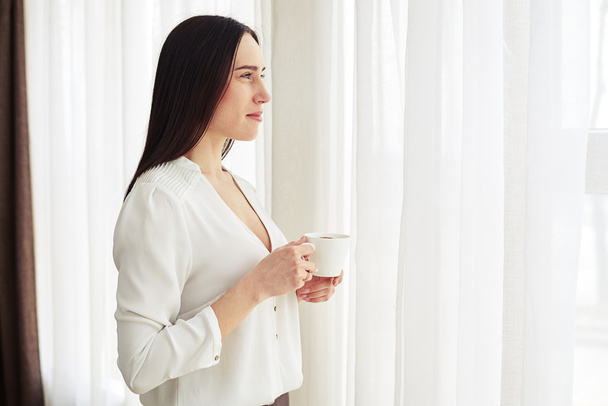 Брюнетка пьет кофе в помещении
 - Фото, изображение