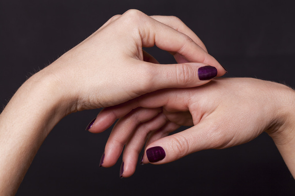 Close-up de cruzado sobre as mãos femininas decoradas com tinta de unha roxa
 - Foto, Imagem