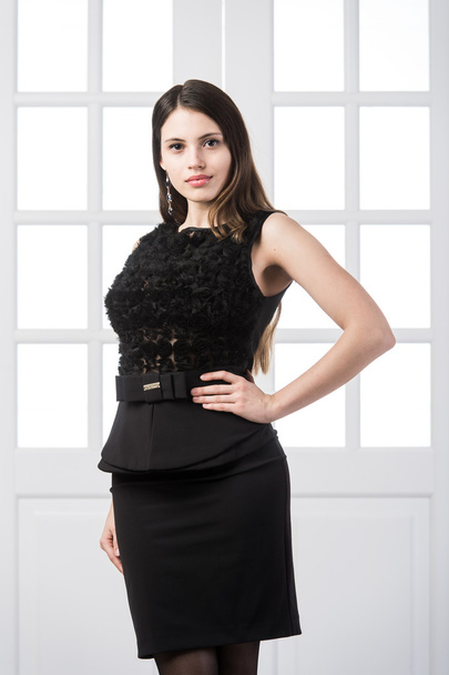 Beautiful woman standing in a black dress over studio loft home interior doors behind - Foto, imagen
