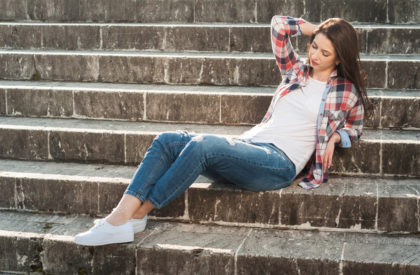 Joven mujer elegante sentado y relajante en escaleras de piedra
 - Foto, Imagen
