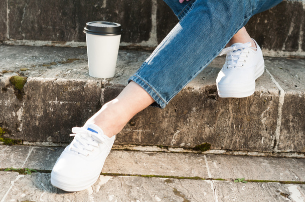 Close up of female legs and coffee on stone stairs - Фото, изображение