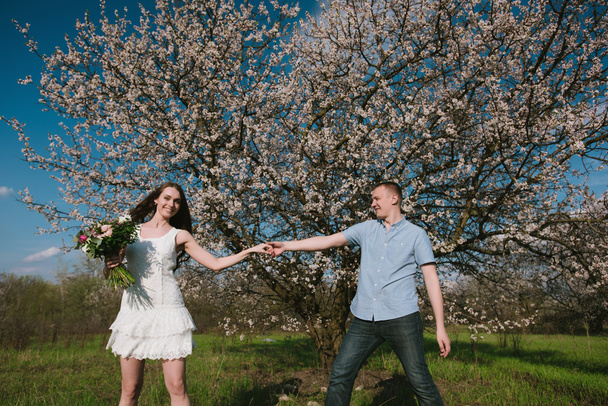 Beautiful young couple dancing and having fun on blue sky background - 写真・画像