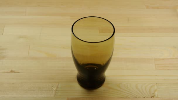 Frische Naturmilch wird aus einer Schüssel in den Klarglasbecher auf dem Holztisch geschüttet. gesundes Essen, Ernährungs- und Getränkekonzept, Nahaufnahme Makro - Filmmaterial, Video
