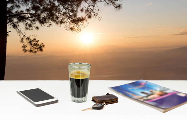 Кофе эспрессо на белом столе и мобильный телефон на закате
  - Фото, изображение