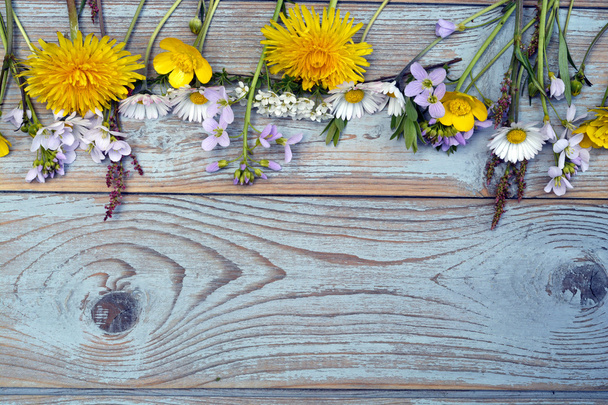 Marguerites, buttercups, pissenlits, herbes sifflantes, fleurs des champs sur un vieux fond de bois gris texturé avec espace de copie vide
 - Photo, image