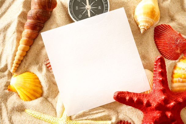 Conchas do mar, bússola e papel sobre areia
 - Foto, Imagem
