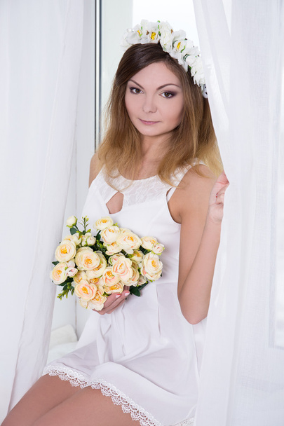 gyönyörű nő rövid fehér menyasszonyi ruha, virágokat ül - Fotó, kép