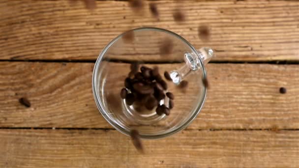 Zpomalený pohyb ze nalití kávová zrna do šálku na starý dřevěný stůl, pohled shora - Záběry, video