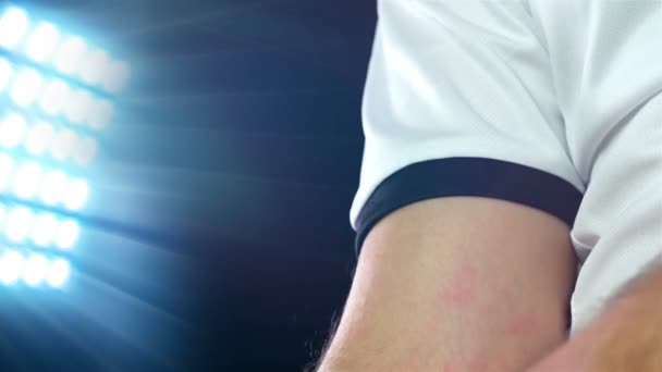Voetbal, voetbalspel. Professionele voetballer in witte outfit zetten kapitein tape, zwarte achtergrond - Video