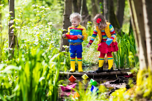 Niños jugando con coloridos botes de papel en un parque
 - Foto, Imagen