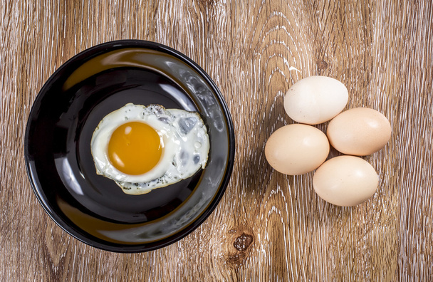 Huevos frescos y fritos sobre fondo de madera
 - Foto, imagen