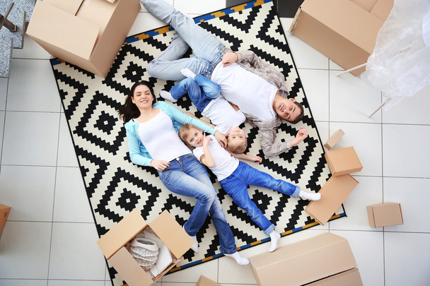 Mozgó koncepció. Boldog család feküdt szőnyeg között karton dobozok, felülnézet - Fotó, kép