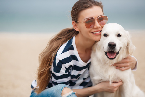 Young woman with a dog on a deserted beach - Foto, Bild