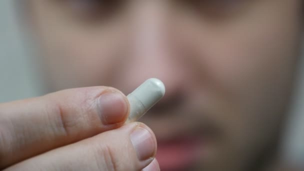 eine extreme Nahaufnahme eines Mannes, der sich eine Pille in den Mund steckt. Mann nimmt Tablette mit Glas Wasser - Filmmaterial, Video
