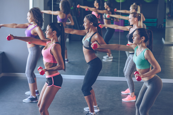 beautiful women exercising with dumbbells at gym - Foto, Bild