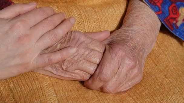 ein junger Mann und eine junge Frau trösten ein altes Paar Hände der Großmutter im Freien. - Filmmaterial, Video