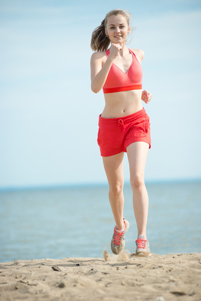 Young lady running at the sunny summer sand beach. Workout.  Jog - Foto, imagen