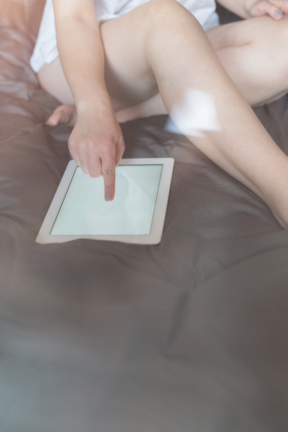 Woman using a tablet computer while lying on her bed, toned phot - Foto, Imagem