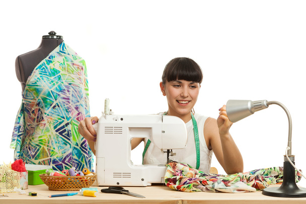 de naaister naait een product op een tafel - Foto, afbeelding
