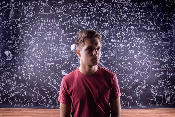 Estudante contra um grande quadro negro com símbolos matemáticos
 - Foto, Imagem