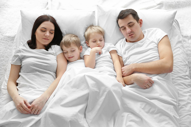 Family sleeping in bed under blanket, closeup - Photo, Image