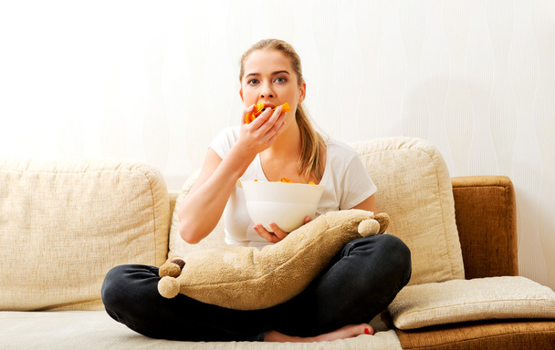 Young woman watching TV and eating chips - Photo, Image