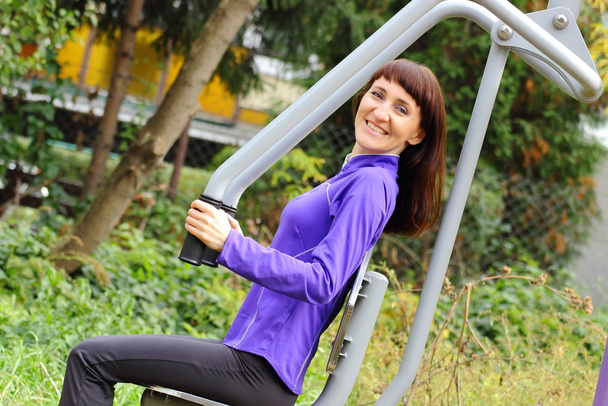 Woman exercising upper body on outdoor gym, healthy lifestyle - Valokuva, kuva