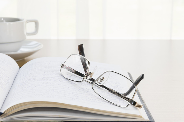  Eyeglasses put on a book with on the desk - Photo, Image