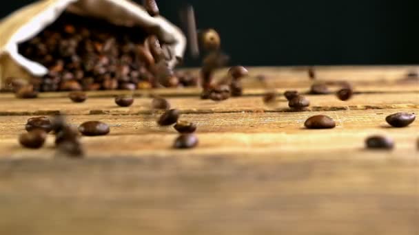 Αργή κίνηση των κόκκων του καφέ που υπάγονται στο ξύλινο τραπέζι - Πλάνα, βίντεο