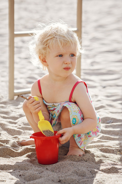 Portrait of cute toddler girl sitting playing with sand and toys outside in park, playground, beach - Photo, Image