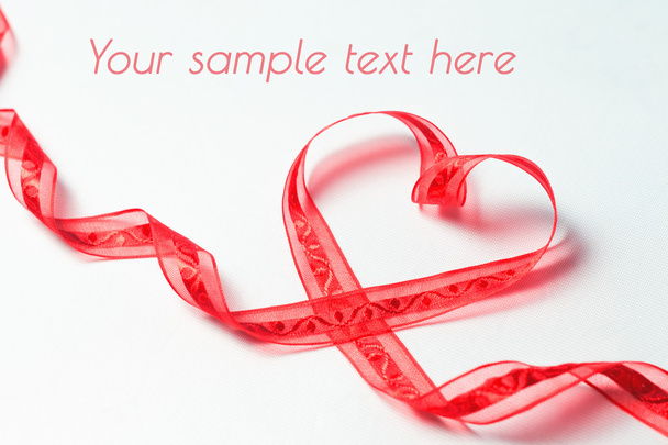 Red ribbon in the form of heart with swirls  - Photo, image