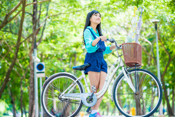 Азіатські мила жінка з велосипеда в саду, громадський парк. - Фото, зображення