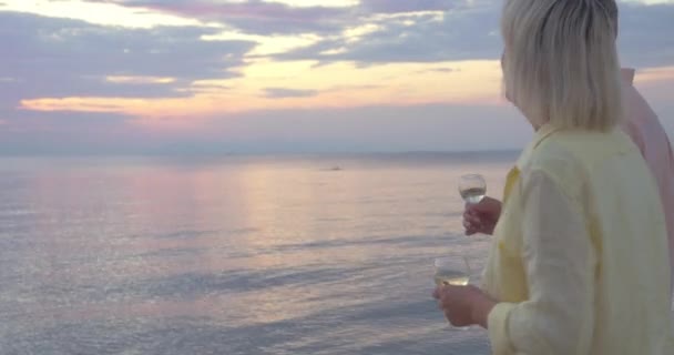 Ώριμο ζευγάρι με ποτήρια κρασιού με τα πόδια από τη θάλασσα - Πλάνα, βίντεο
