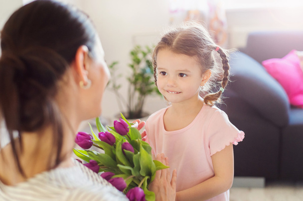母の日に、小さな女の子がお母さんに花をあげる - 写真・画像
