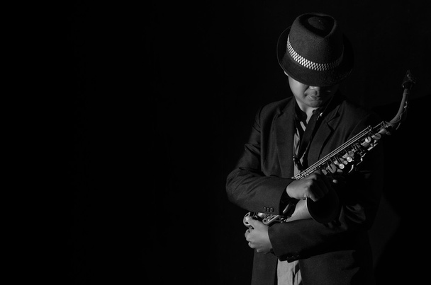 A saxophone player in a dark background, black and white tone - Foto, Imagem