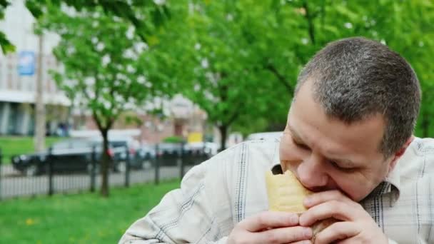 Portret van een zeer hongerig mens eet junkfood - Video
