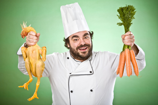 smiling and wild chef show vegetables and chicken isolated on green  - Foto, afbeelding