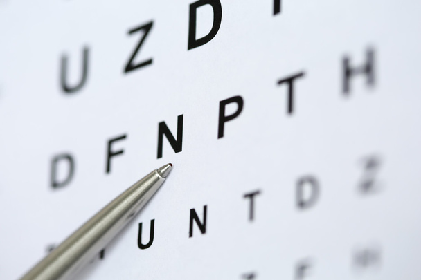 Серебряная шариковая ручка, указывающая на букву в таблице проверки зрения
 - Фото, изображение