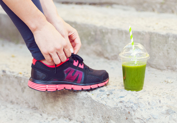 Green detox smoothie cup and woman lacing running shoes before w - Foto, afbeelding
