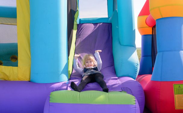 Cute little fair haired girl on a bouncy castle - Photo, Image