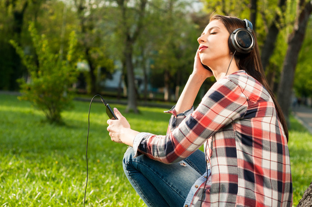Mujer escuchando música afuera en el parque usando auriculares
 - Foto, imagen