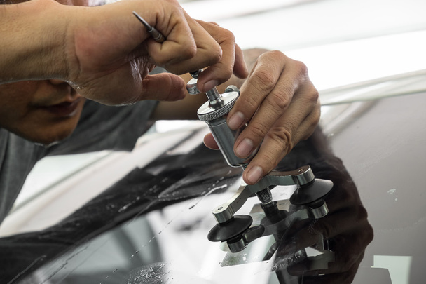 A man using repairing equipment to fix damaged windshield - Фото, изображение