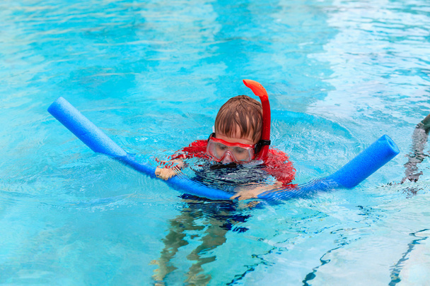 Маленький хлопчик вчиться плавати наодинці з локшиною для басейну
 - Фото, зображення