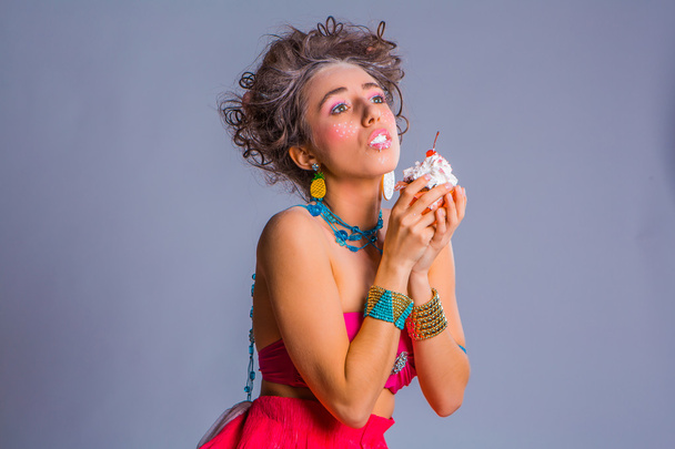 Beautiful girl eats chokolate creamy muffin with cherry - Photo, Image