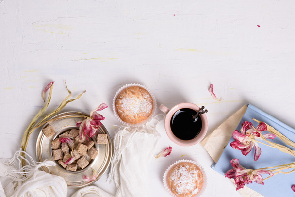 Cakes, cup of coffee and pink tulip flowers, romantic breakfast background. Copy space, top view.  - Photo, image