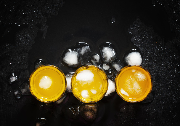 Yellow cocktails with ice on wet dark background - Foto, imagen